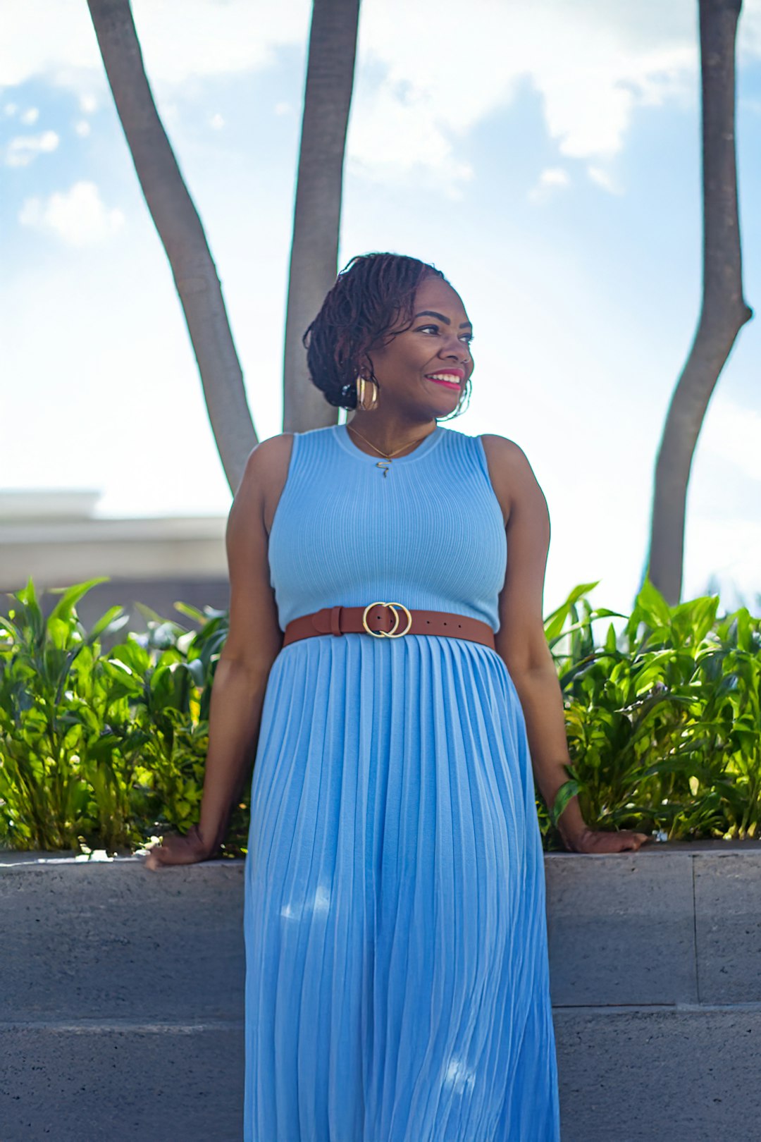 A woman in a blue dress standing next to a wall