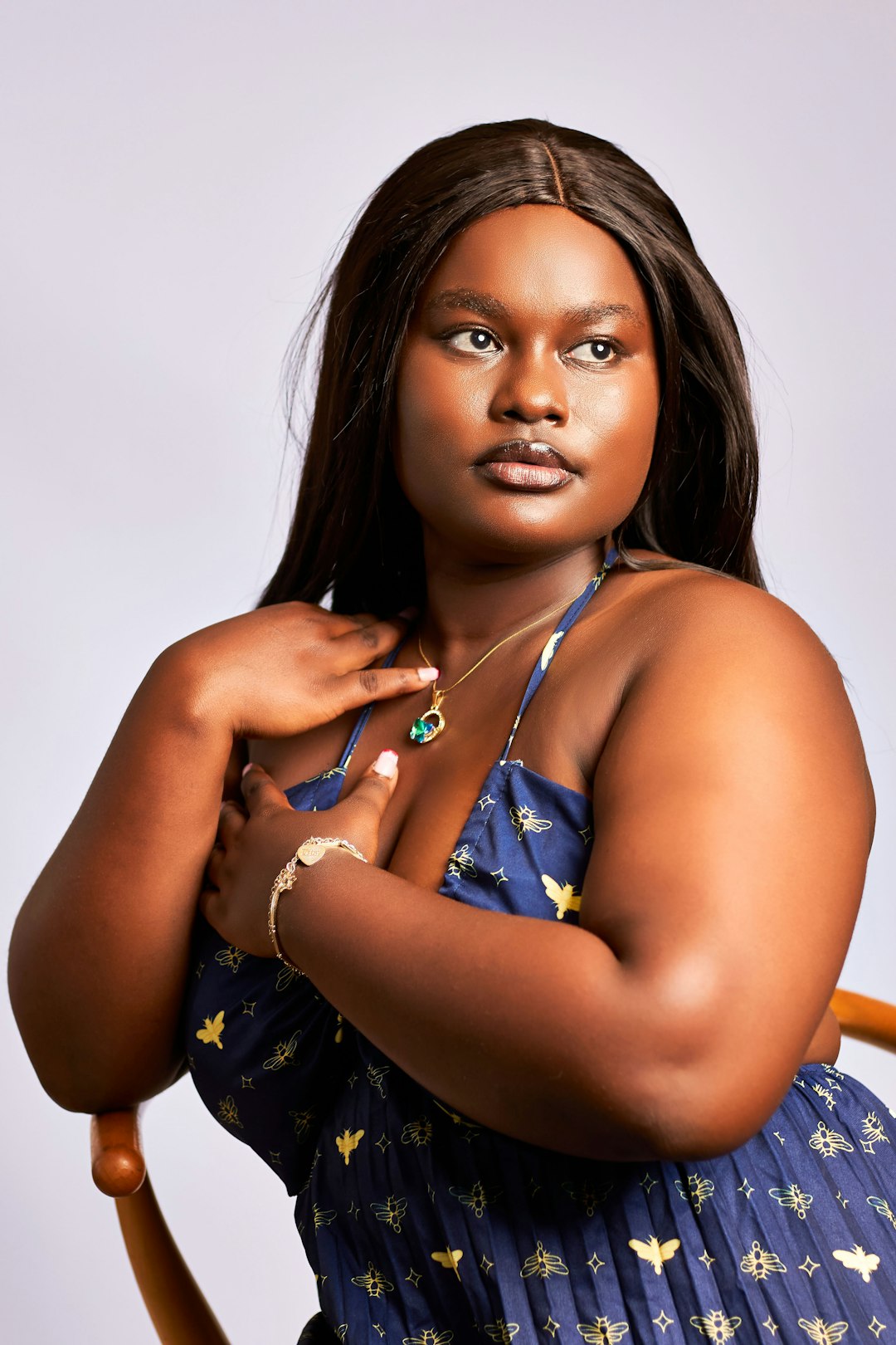 Body Neutrality vs. Body Positivity in Plus-Size Fashion: Key Differences and How to Choose What Fits You woman in a navy blue dress with yellow bee patterns and a gold necklace
